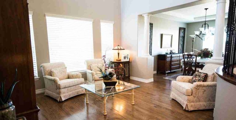 Bright period living room with cream armchairs and oak flooring after an eco-friendly home update