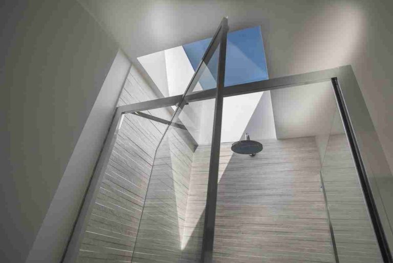Bright stairwell with glass balustrade and roof glazing in a Fulham house renovation