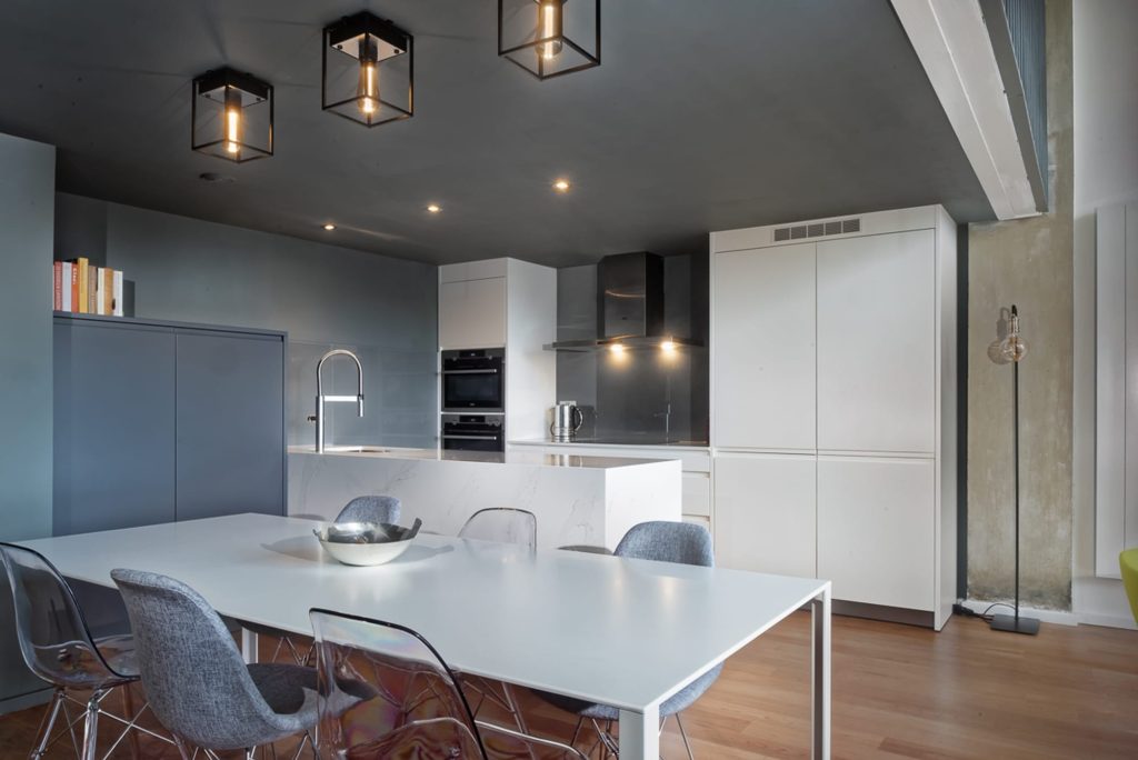 White kitchen island with pendant lights in an industrial style loft apartment, professionally measured and fitted