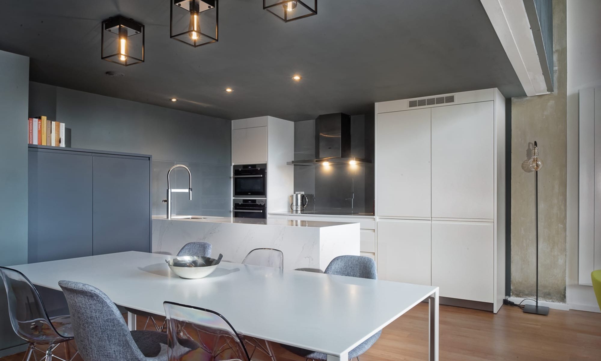 White kitchen island with pendant lights in an industrial style loft apartment, professionally measured and fitted