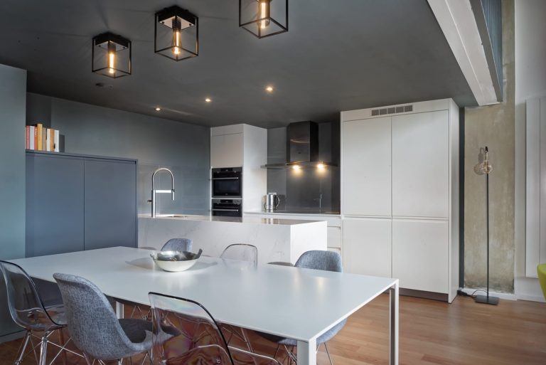White kitchen island with pendant lights in an industrial style loft apartment, professionally measured and fitted