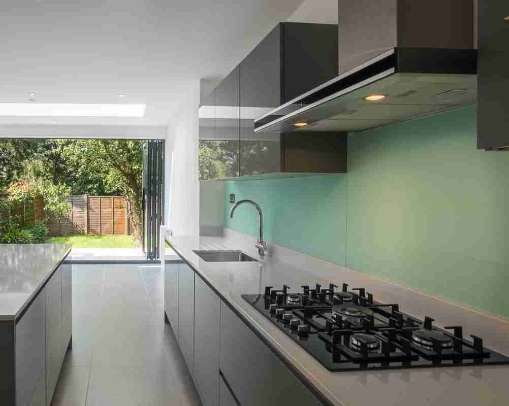 Green glass splashback and integrated extractor in a Fulham kitchen extension