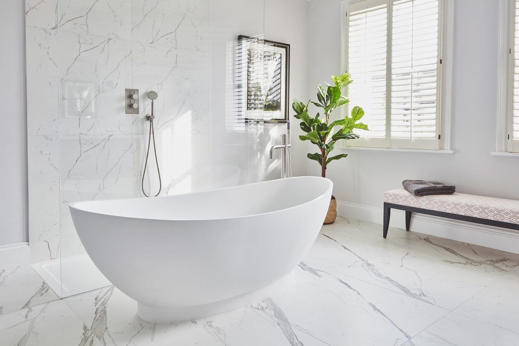 Freestanding oval bath in a white London bathroom renovation with wood-effect flooring