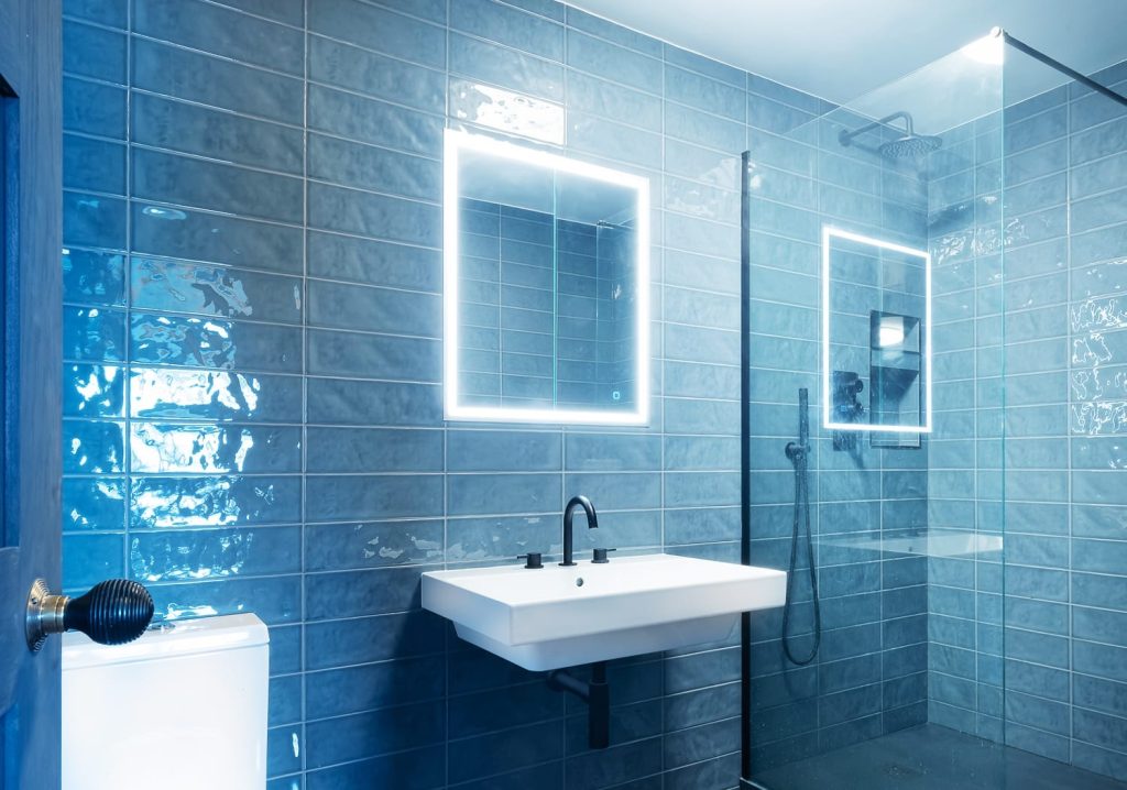 Fulham bathroom renovation with backlit LED mirror, blue metro tiles and a glass shower screen