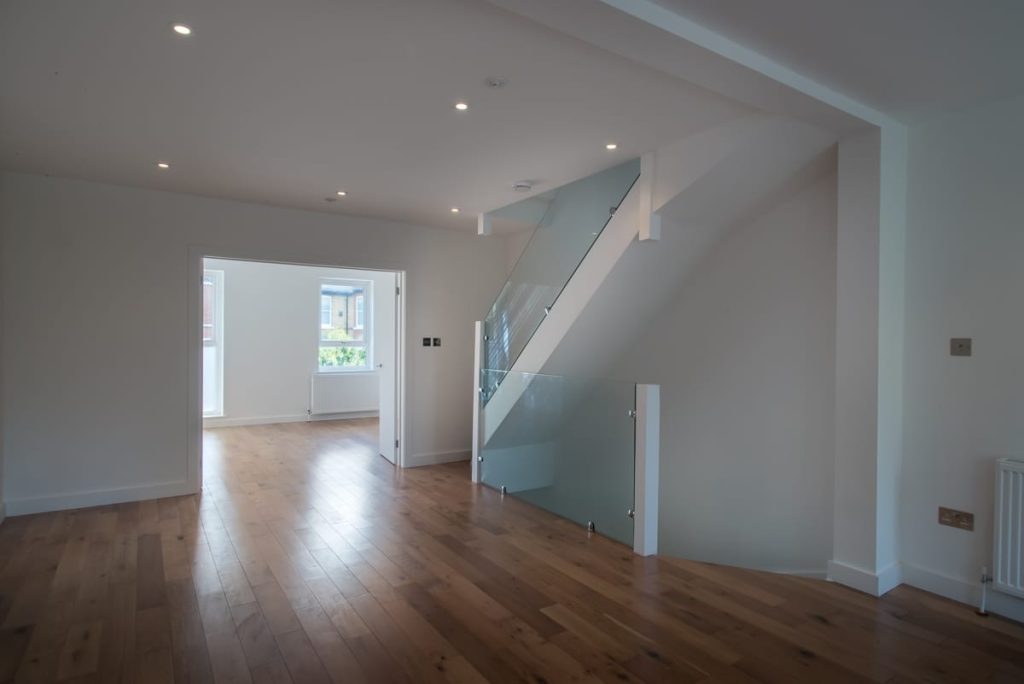 Redecorated empty room with oak flooring and freshly painted white walls